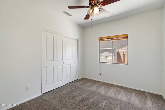 unfurnished bedroom with baseboards, a closet, dark colored carpet, and visible vents