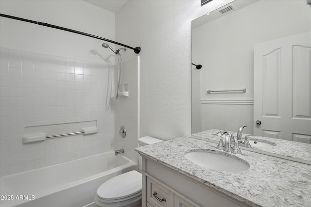 bathroom featuring visible vents, vanity, toilet, washtub / shower combination, and a textured wall
