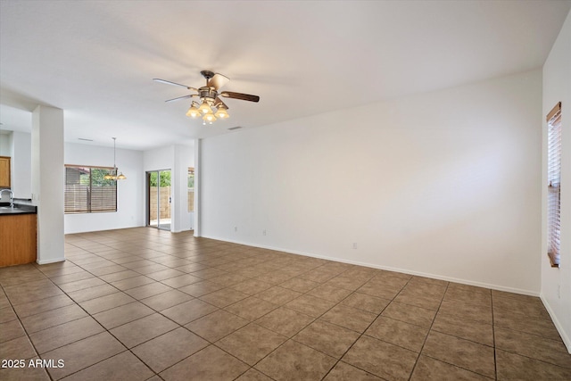 unfurnished living room featuring ceiling fan, visible vents, tile patterned flooring, a sink, and baseboards
