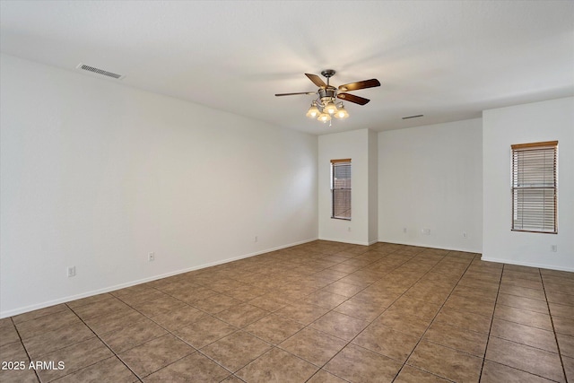 spare room featuring baseboards, tile patterned flooring, a ceiling fan, and visible vents
