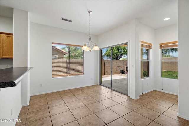 unfurnished dining area with light tile patterned flooring, a chandelier, a healthy amount of sunlight, and visible vents
