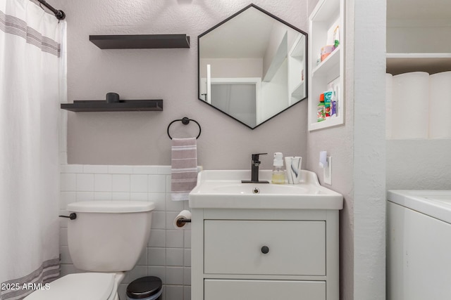 1600 N Saba St Unit 143, Chandler, AZ 85225 - bathroom featuring washer / dryer, vanity, toilet, tile walls, and a wainscoted wall