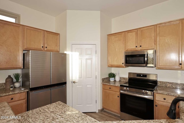 kitchen featuring light stone countertops, appliances with stainless steel finishes, and light hardwood / wood-style flooring