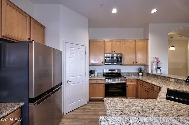 kitchen featuring sink, light hardwood / wood-style flooring, decorative light fixtures, kitchen peninsula, and stainless steel appliances