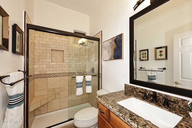 bathroom featuring vanity, toilet, and a shower with shower door