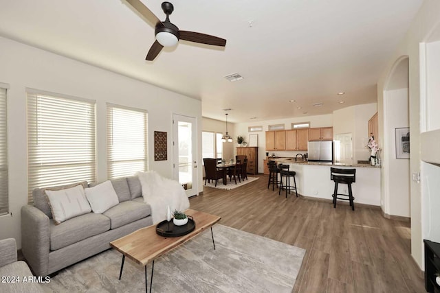 living room with ceiling fan, light wood-type flooring, and sink