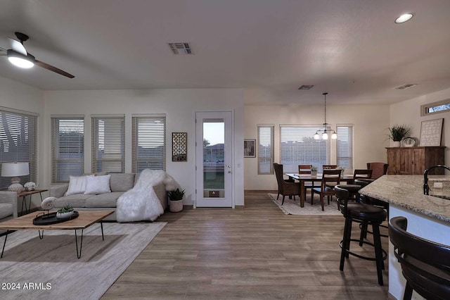 living room with light hardwood / wood-style flooring, ceiling fan with notable chandelier, and sink