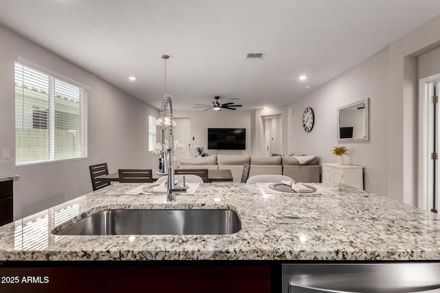 17437 W Via De Luna Dr, Surprise, AZ 85387 - kitchen featuring light stone counters, a sink, dishwasher, a ceiling fan, and open floor plan