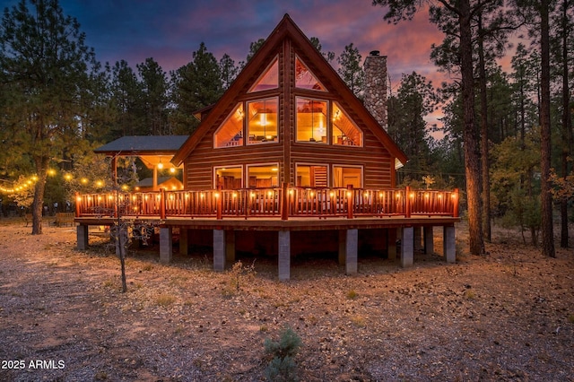 back of property with a wooden deck and a chimney