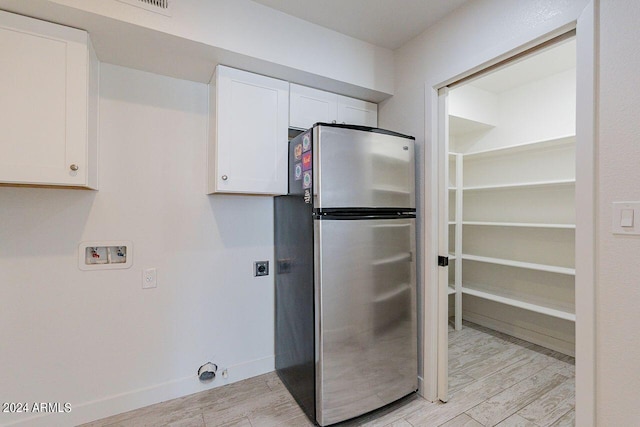 kitchen featuring white cabinets, light hardwood / wood-style flooring, and stainless steel refrigerator