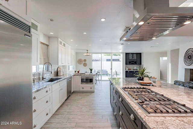 kitchen with white cabinets, built in appliances, light stone countertops, and expansive windows