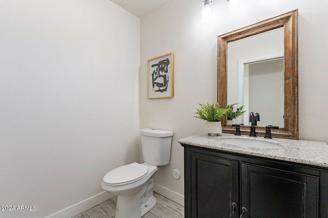 bathroom with hardwood / wood-style flooring, toilet, and vanity