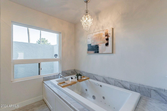 bathroom with a tub to relax in and an inviting chandelier