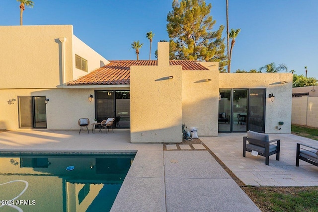 rear view of property with a fenced in pool and a patio area