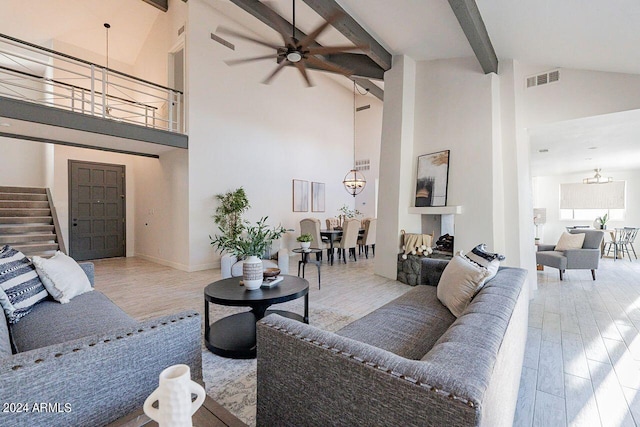 living room featuring ceiling fan with notable chandelier, light hardwood / wood-style flooring, beam ceiling, and high vaulted ceiling