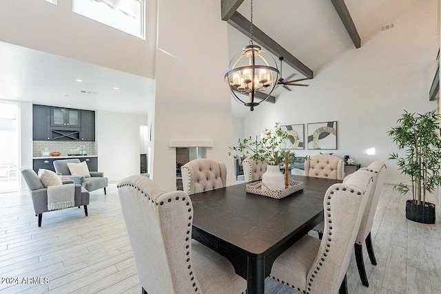 dining space featuring an inviting chandelier, light hardwood / wood-style flooring, beam ceiling, and high vaulted ceiling