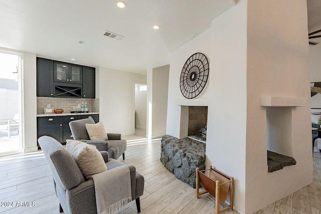 living room with light hardwood / wood-style flooring and a stone fireplace