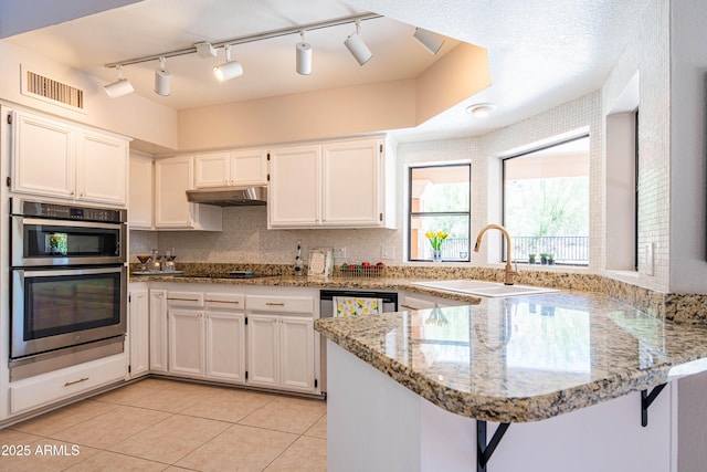 11025 N 10th St, Phoenix, AZ 85020 - kitchen featuring a peninsula, stainless steel appliances, white cabinets, light stone countertops, and under cabinet range hood