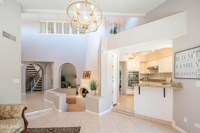 11025 N 10th St, Phoenix, AZ 85020 - foyer with light tile patterned floors, a chandelier, a high ceiling, and stairway