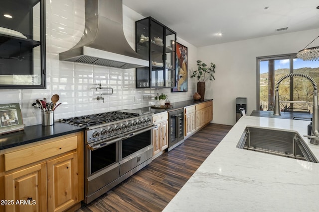 kitchen featuring beverage cooler, a sink, visible vents, double oven range, and wall chimney exhaust hood