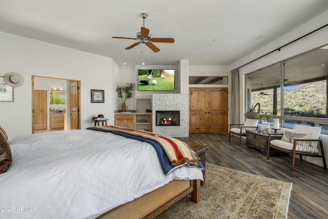 bedroom featuring a warm lit fireplace and wood finished floors