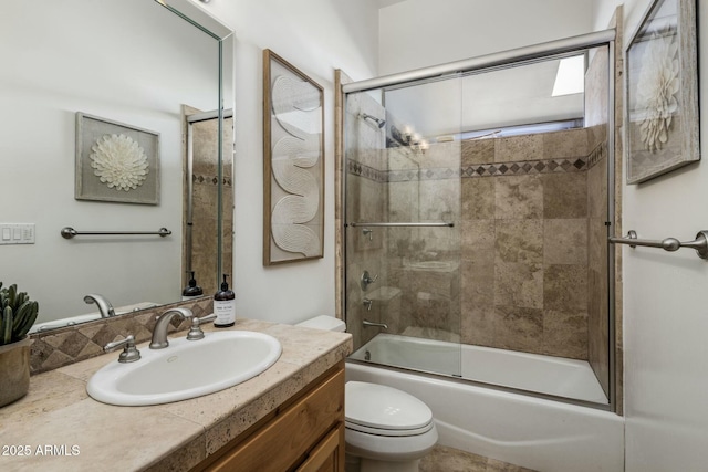 full bath with vanity, toilet, and bath / shower combo with glass door