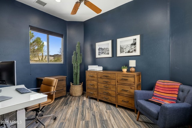 office space featuring a ceiling fan, visible vents, and wood finished floors