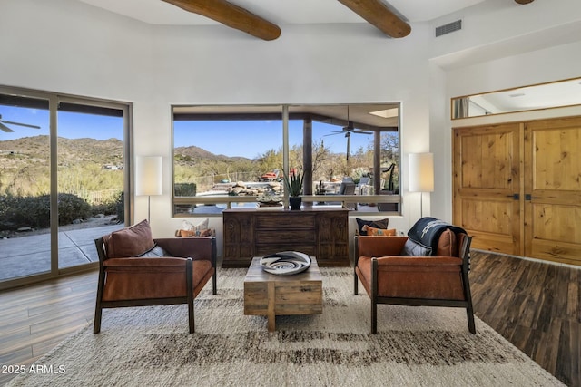 sitting room featuring beamed ceiling, wood finished floors, visible vents, and a healthy amount of sunlight