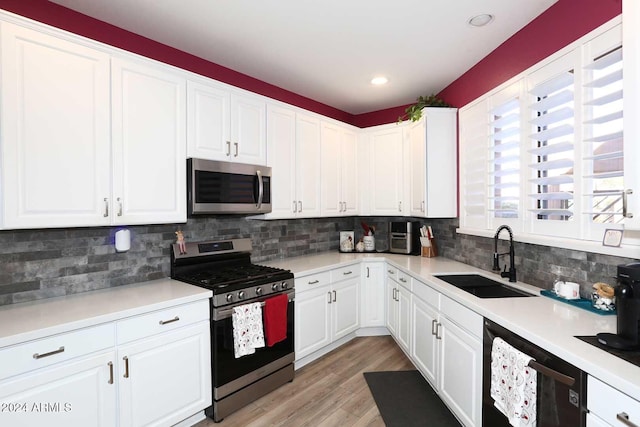 kitchen featuring sink, tasteful backsplash, white cabinetry, appliances with stainless steel finishes, and light wood-type flooring