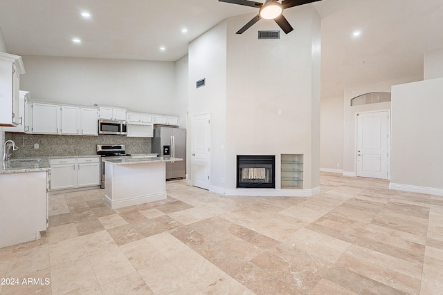 kitchen with a center island, backsplash, high vaulted ceiling, white cabinets, and appliances with stainless steel finishes