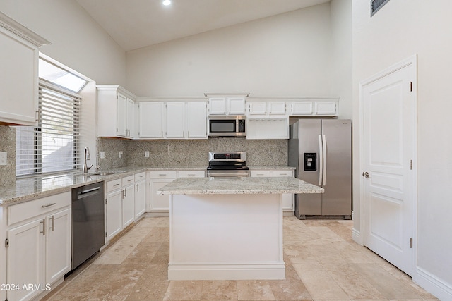 kitchen with a center island, light stone counters, white cabinetry, and stainless steel appliances