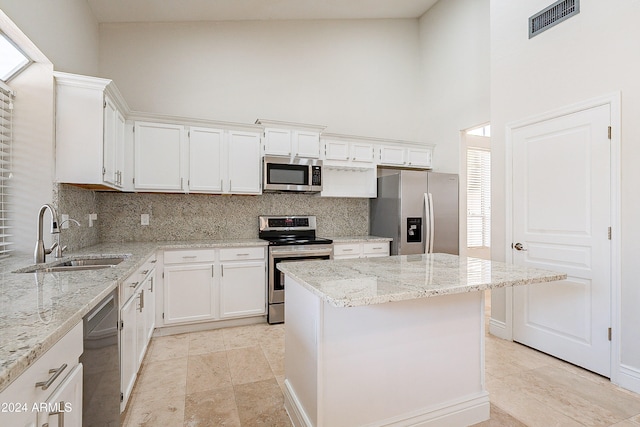 kitchen featuring light stone countertops, stainless steel appliances, sink, high vaulted ceiling, and white cabinetry