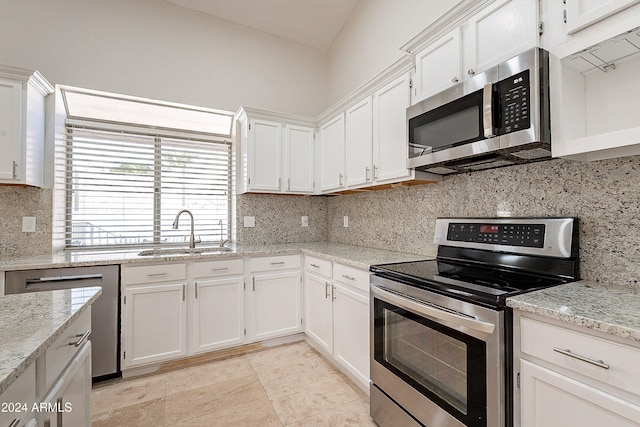 kitchen featuring light stone countertops, tasteful backsplash, stainless steel appliances, sink, and white cabinets