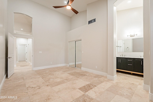 spare room featuring ceiling fan, sink, and a high ceiling