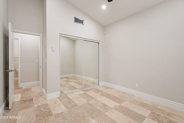 unfurnished bedroom with high vaulted ceiling and a closet