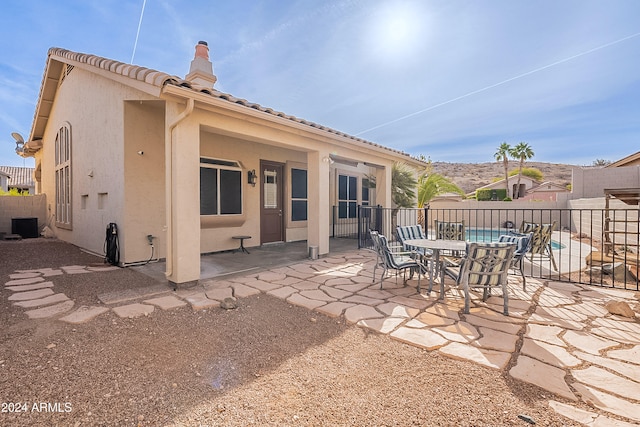 rear view of house featuring a fenced in pool, a patio, and central AC unit