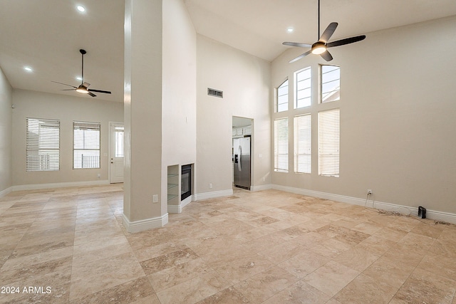 unfurnished living room with a high ceiling and ceiling fan