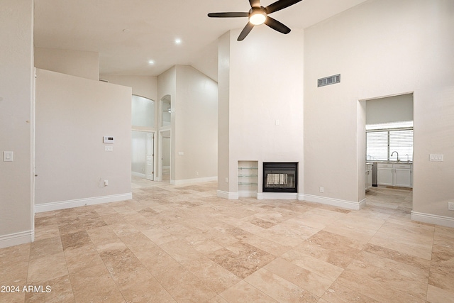 unfurnished living room with ceiling fan, sink, and high vaulted ceiling