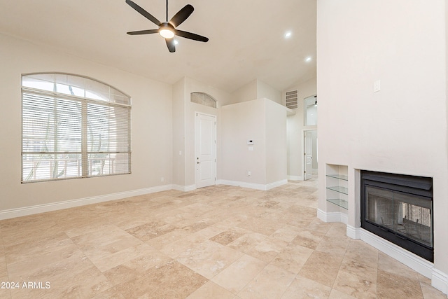 unfurnished living room featuring ceiling fan and built in shelves