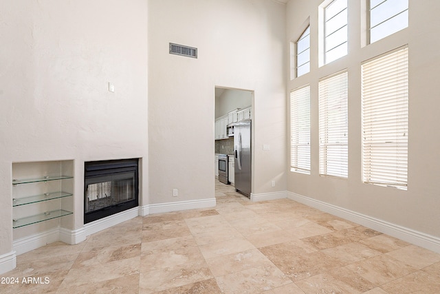 unfurnished living room featuring a towering ceiling