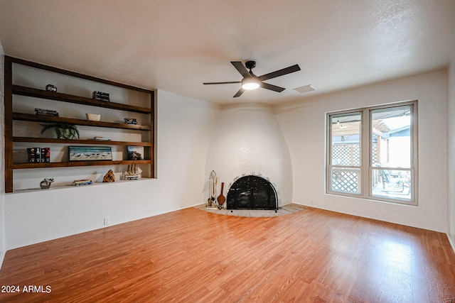 unfurnished living room featuring a large fireplace, ceiling fan, and hardwood / wood-style flooring