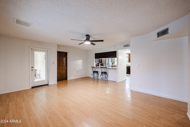 unfurnished living room with ceiling fan, a textured ceiling, and light wood-type flooring