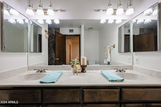 bathroom featuring toilet and double sink vanity