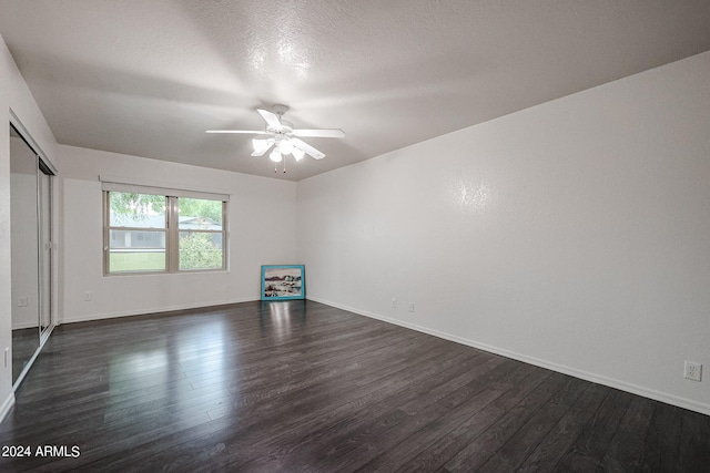 empty room featuring dark hardwood / wood-style floors, ceiling fan, and a textured ceiling