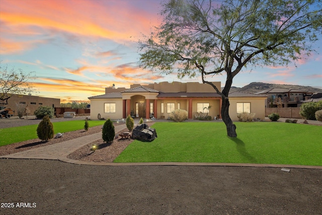 view of front of home with fence, a front lawn, and stucco siding