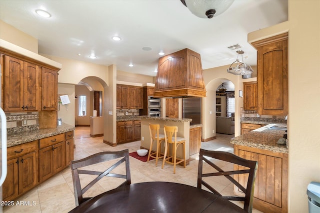 kitchen with arched walkways, a breakfast bar area, a kitchen island, and pendant lighting