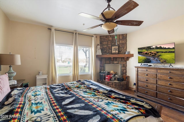 bedroom with a fireplace, a ceiling fan, and wood finished floors