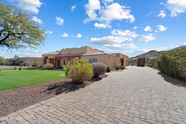 exterior space with a mountain view, fence, decorative driveway, stucco siding, and a front yard