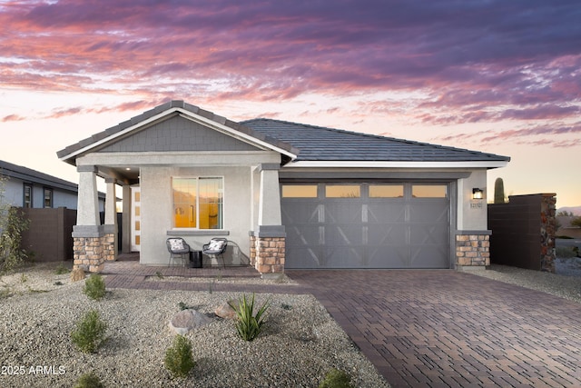 view of front of home with decorative driveway, stone siding, a porch, and stucco siding