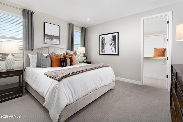 bedroom featuring light carpet, recessed lighting, a walk in closet, and baseboards